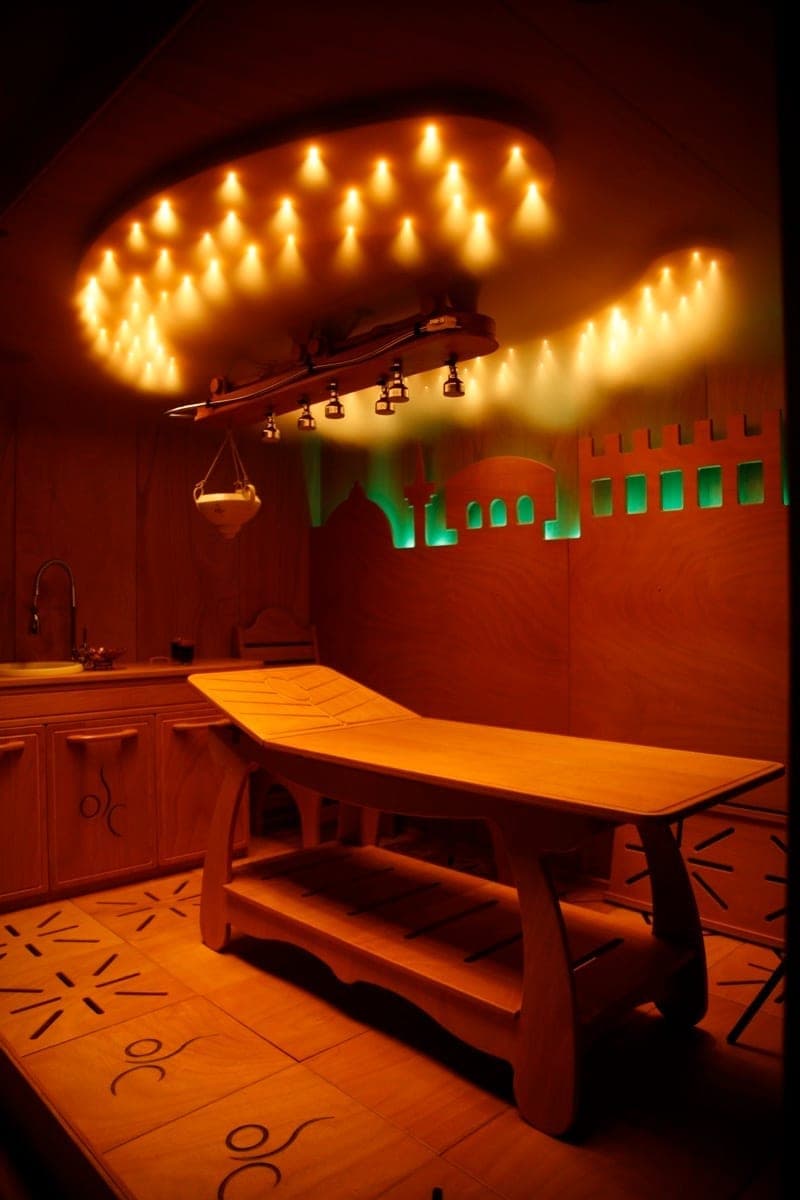 Interno della suite per massaggi con lettino in legno e illuminazione calda