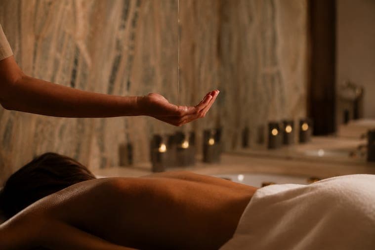Rituale con olio caldo versato sulla schiena, tra candele e pareti in marmo