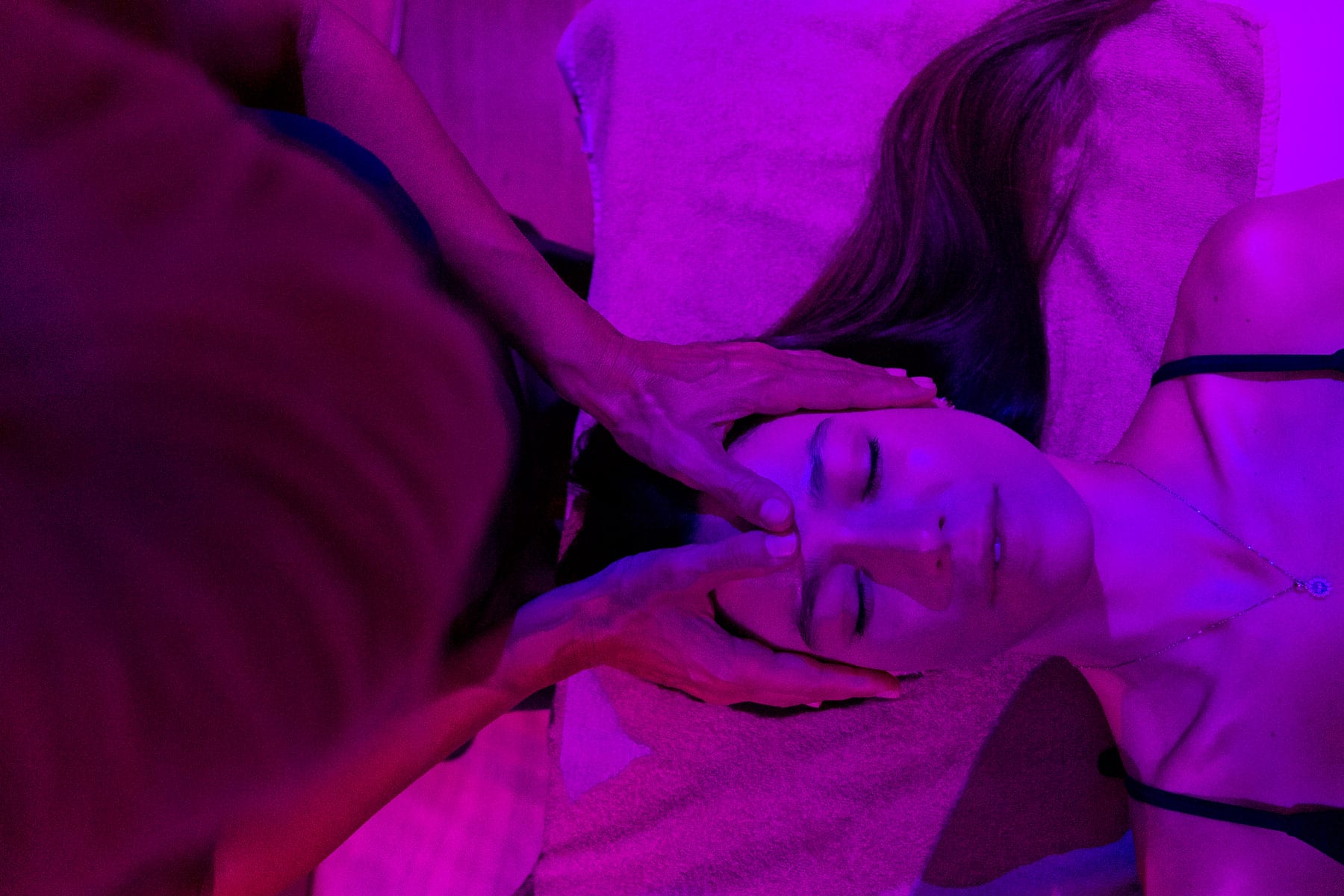 Operatrice che versa olio da una ciotola sulle mani, sopra la schiena di una cliente