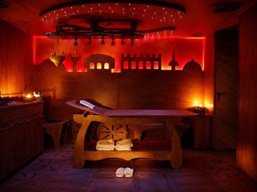 Suite privata con lettino in legno, luci calde e silhouette illuminata sulla parete