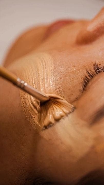 Applicazione di una maschera cremosa sul viso con pennello a ventaglio